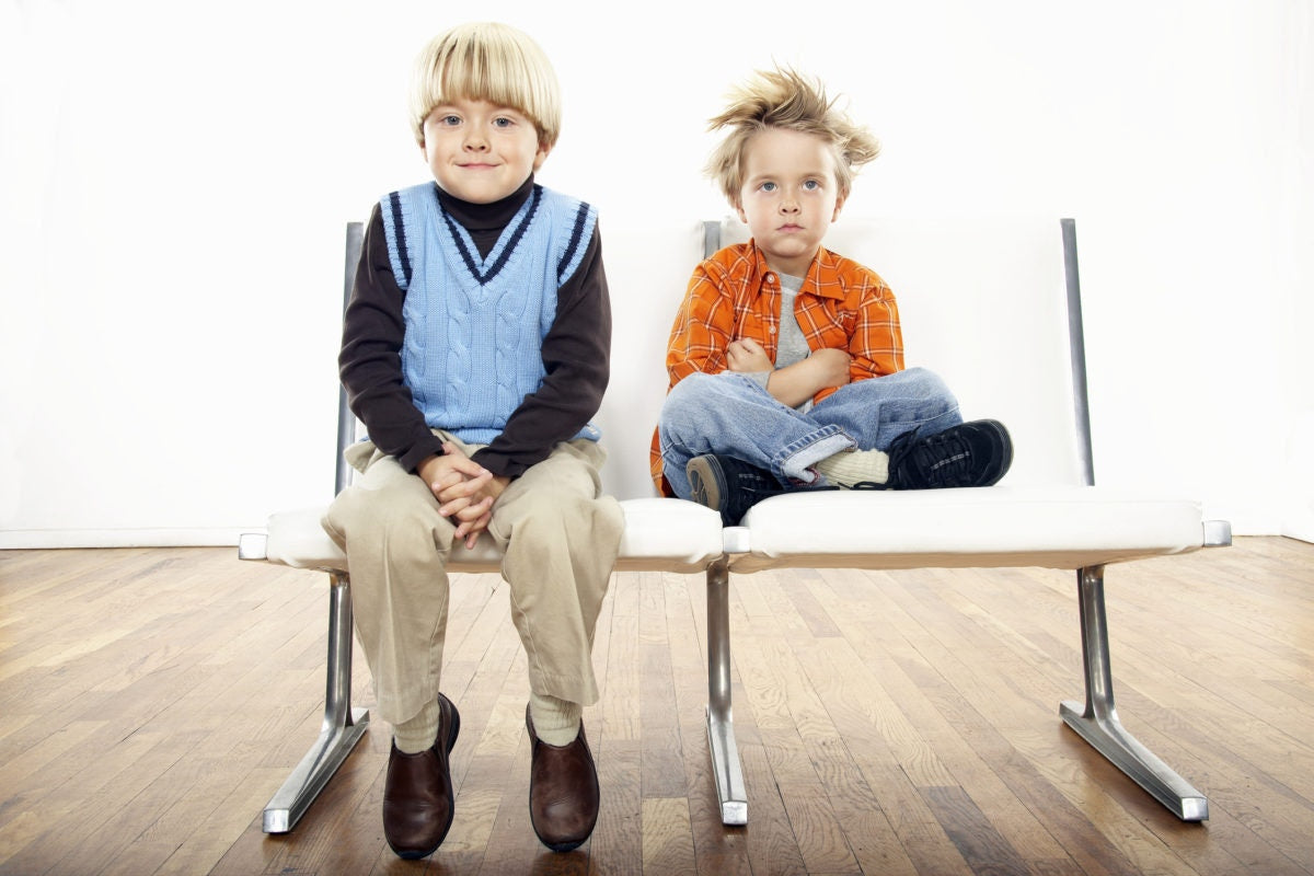 Two kids are sitting on a chair by watching something