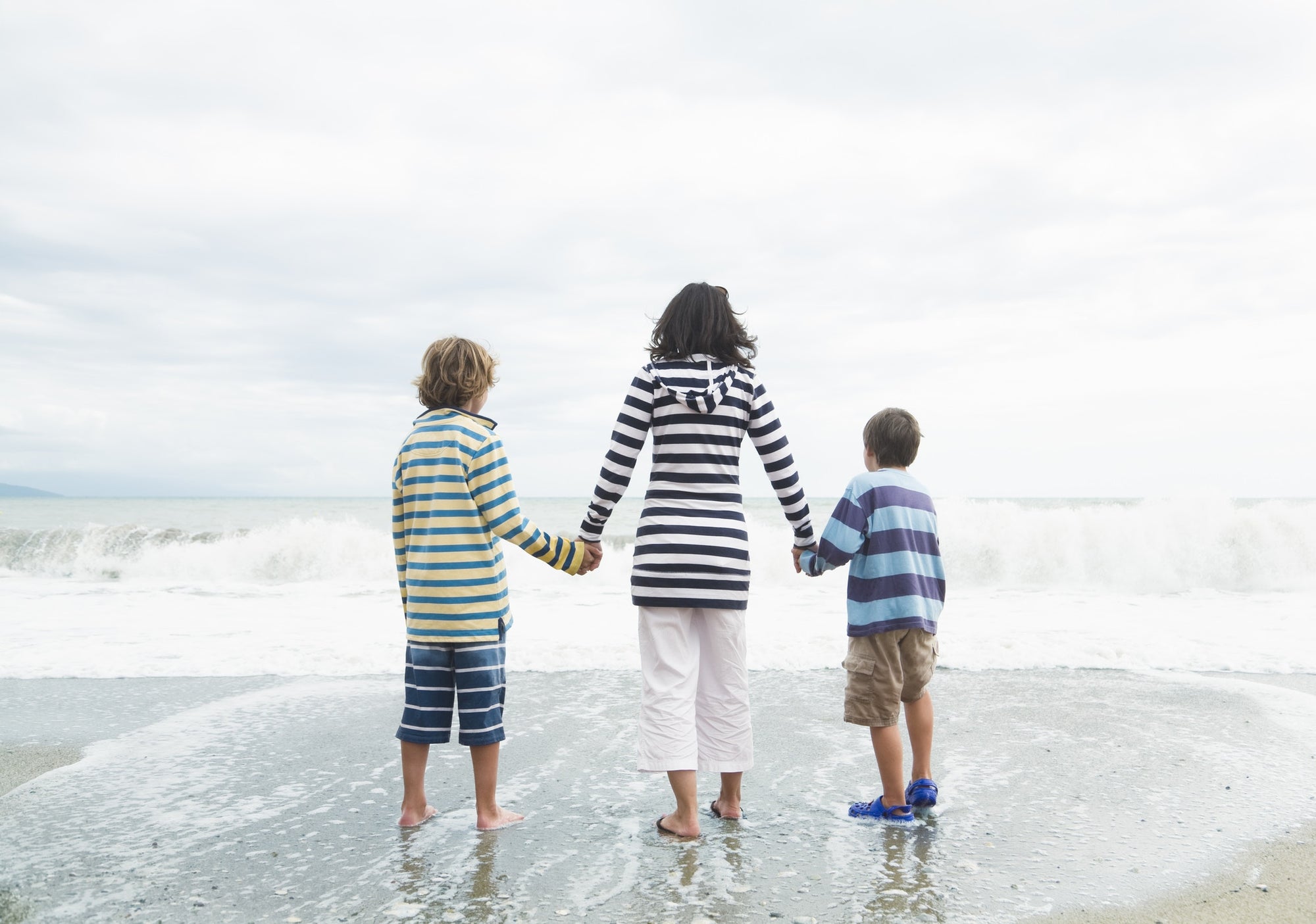 Mom And Her two sons Walk Hand In Hand At The Beach