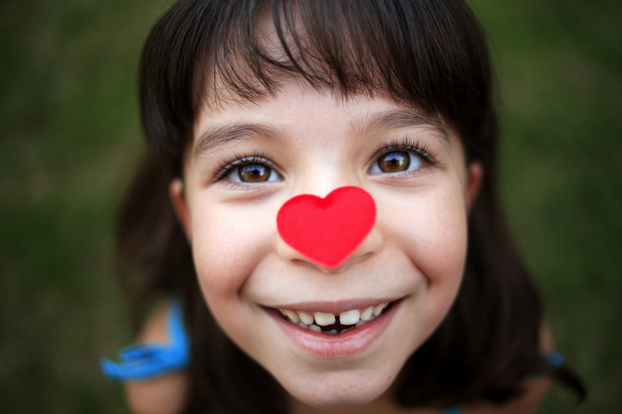 little girl looking up,heart shaped paper on her nose