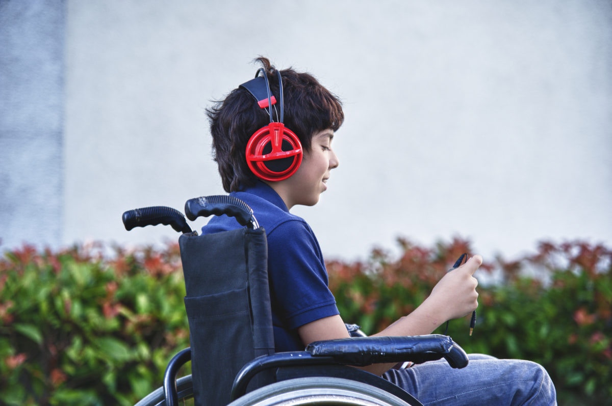 A boy sitting in a whell chair listening music