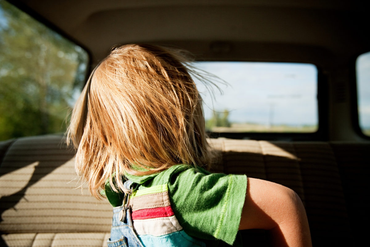 A girl sitting in a car seeing behind