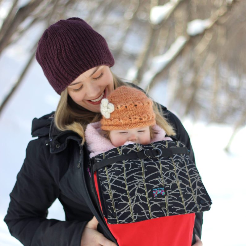 Little baby girl and her mother walking outside in winter Mother is holding her baby babywearing the carrier