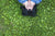 lady lying on grass field covering her face with hands