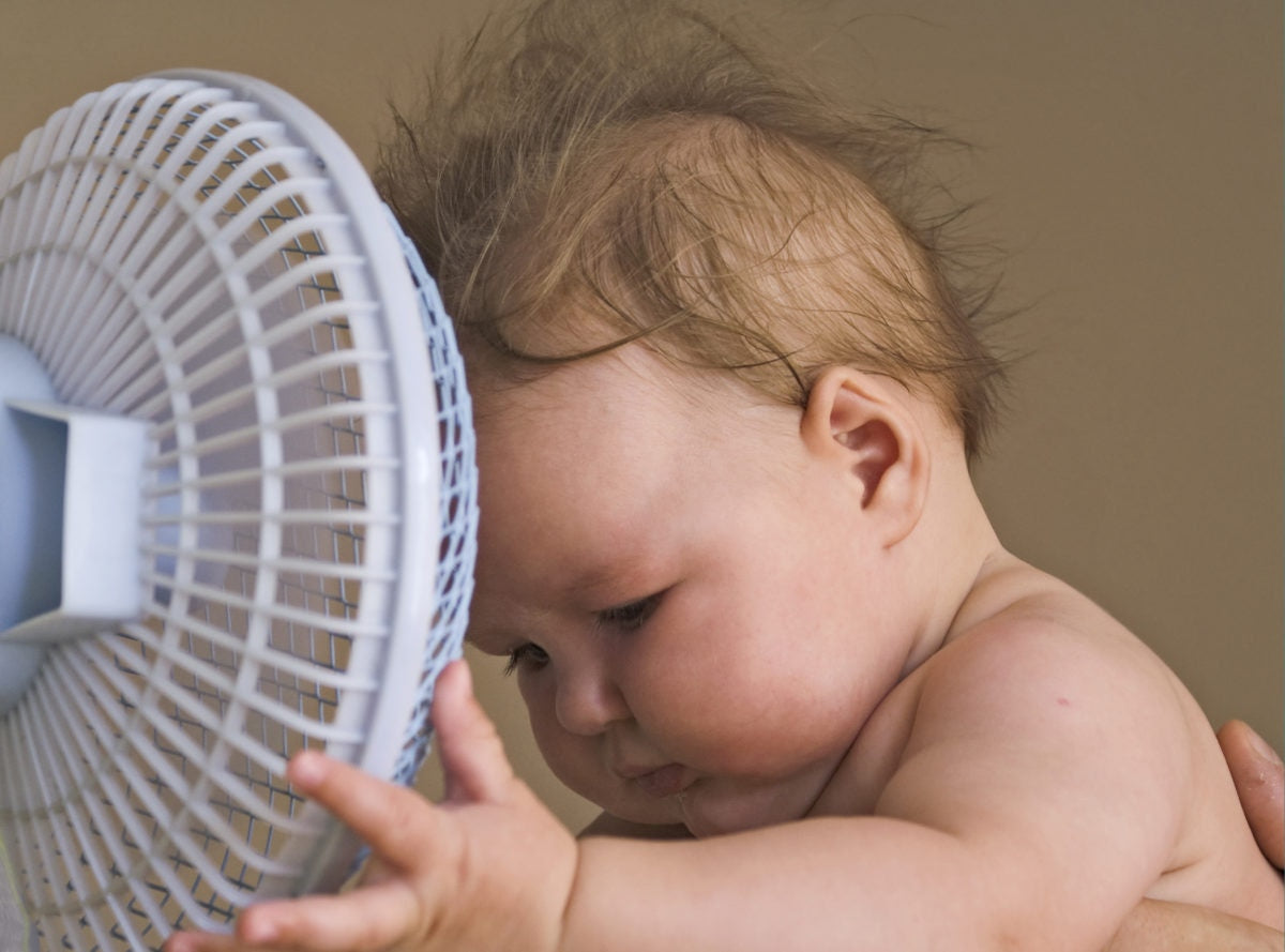 baby standing in front of fan