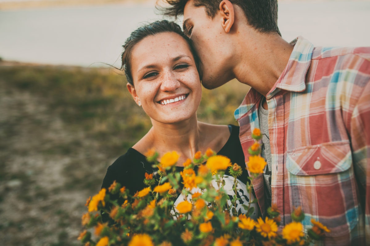 Boy gives girl a bouquet of wild flowers and kisses her