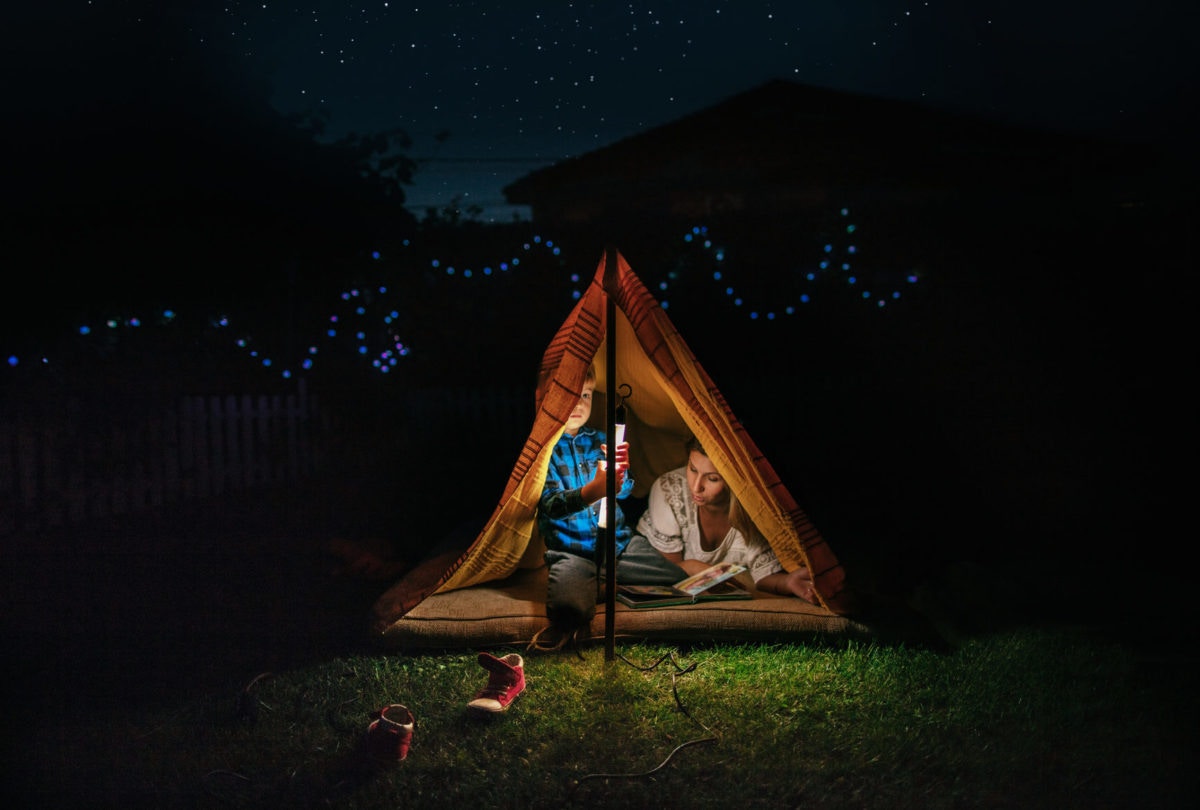 Mother and son reading a bed time story on a tent at home