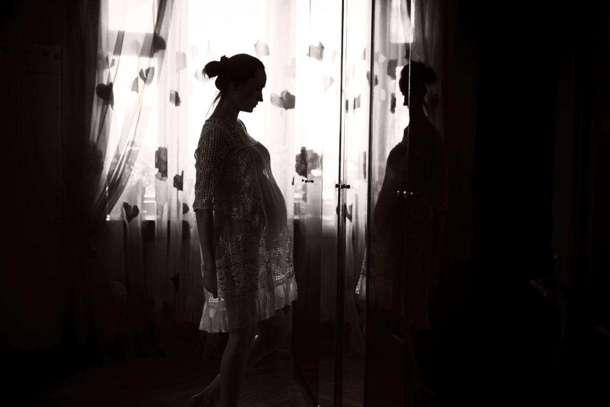 Young pregnant woman looking in mirror