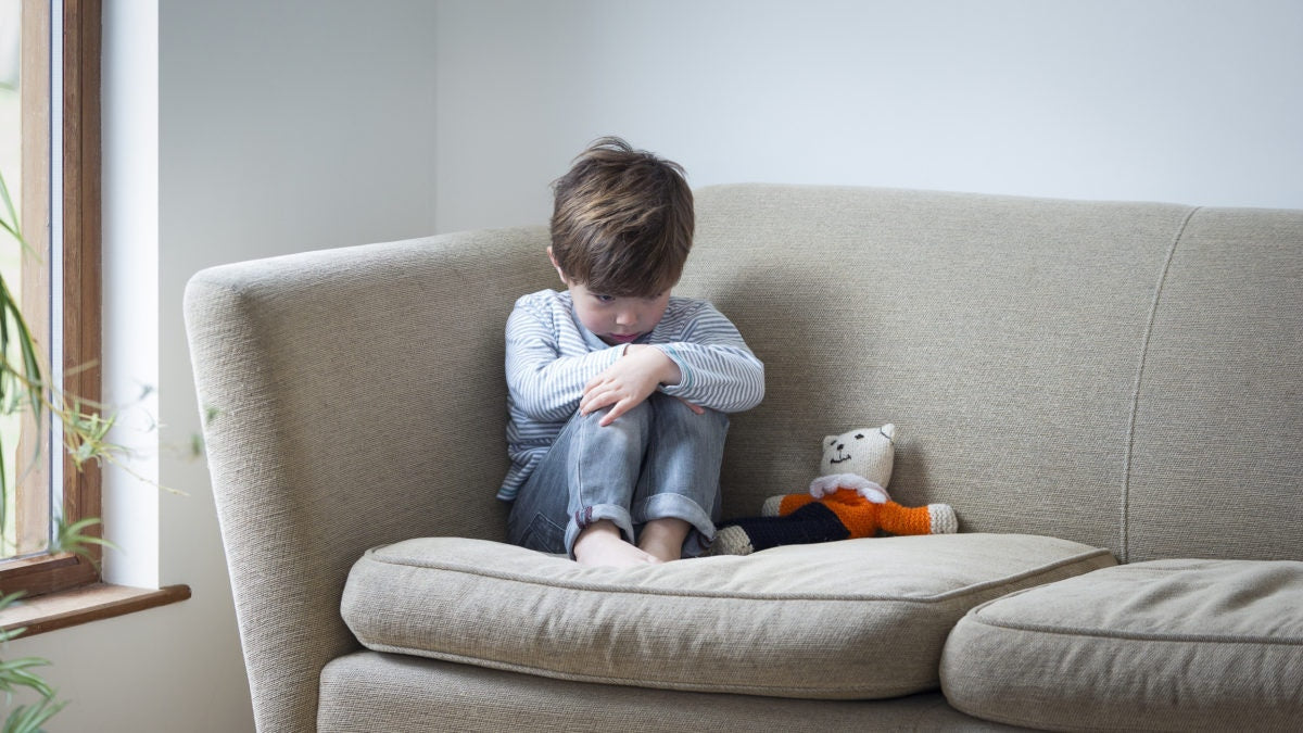 A child is sitting on a sofa with emotional
