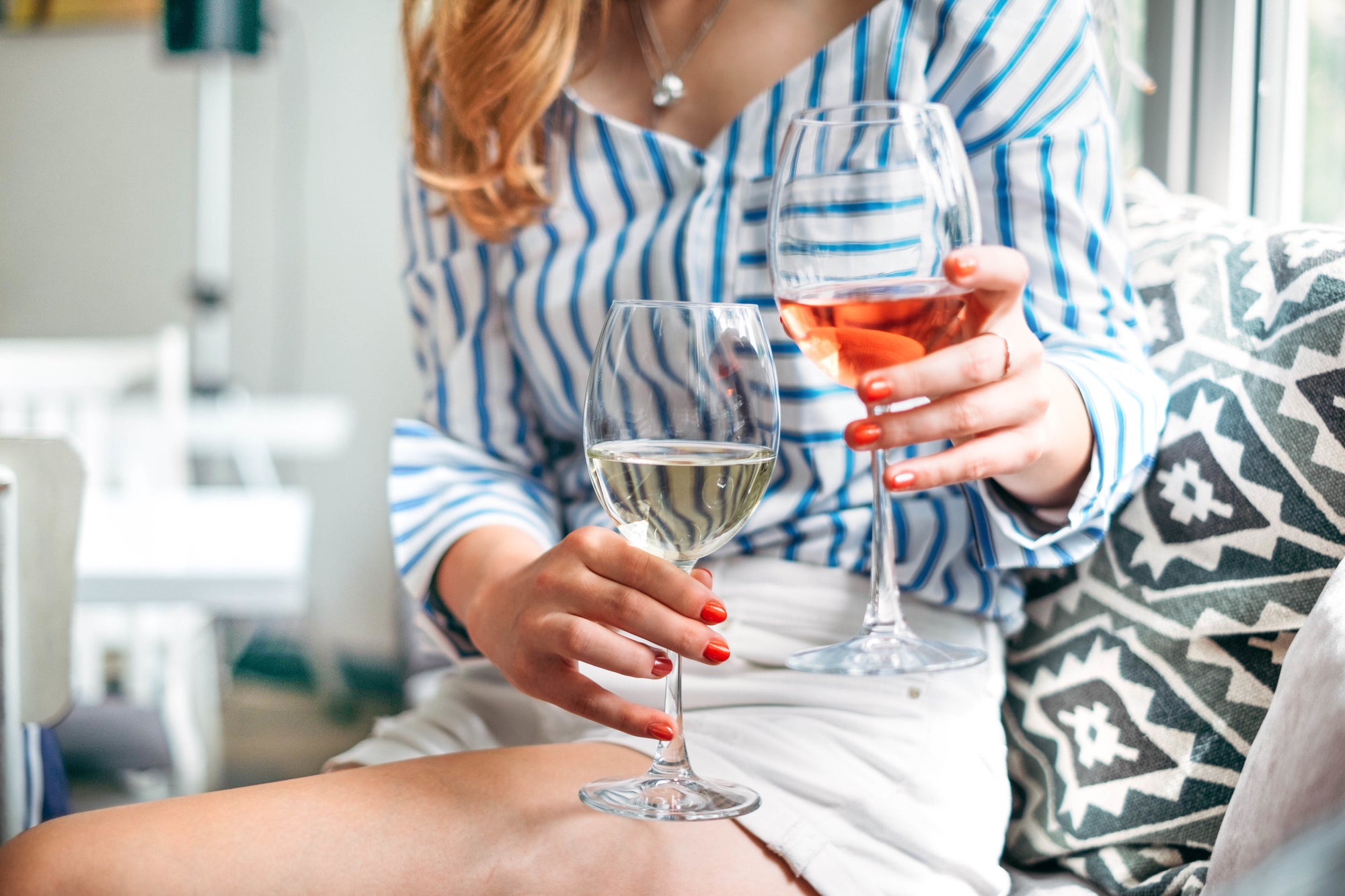 beautiful women sitting on couch holding glass of red and white wine