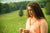 woman with curly hair in a orange hoodie against nature background
