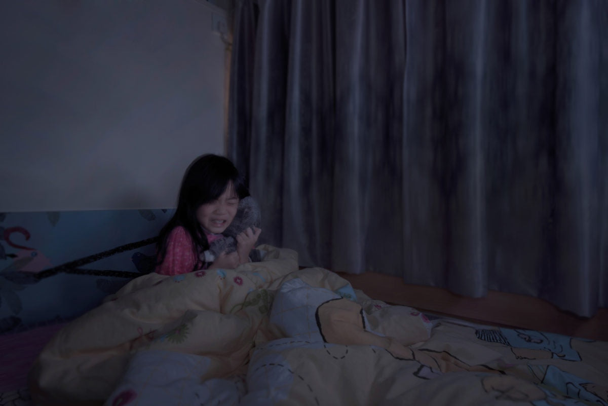 little girl with toy crying in the bed