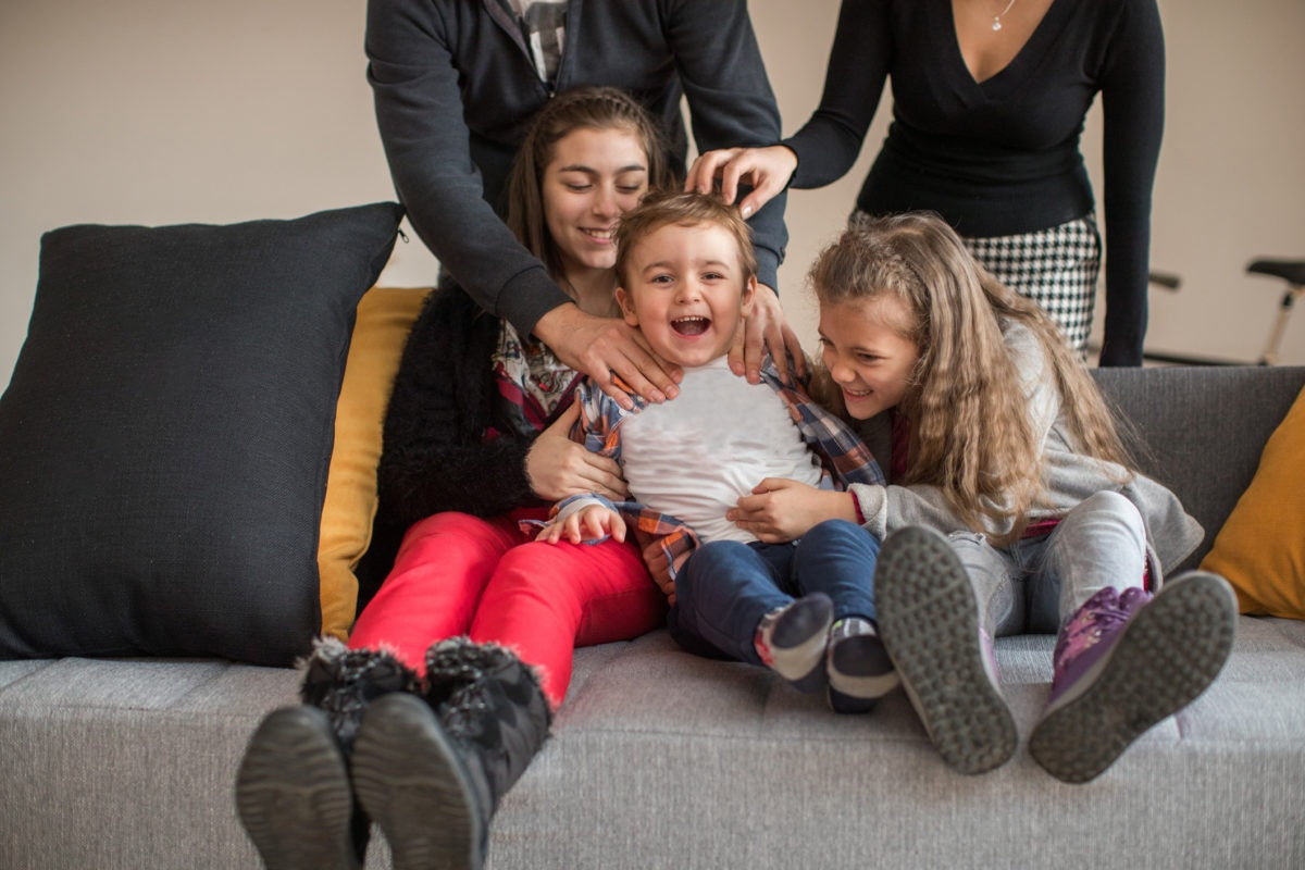 sisters playing with her cute little brother on couch