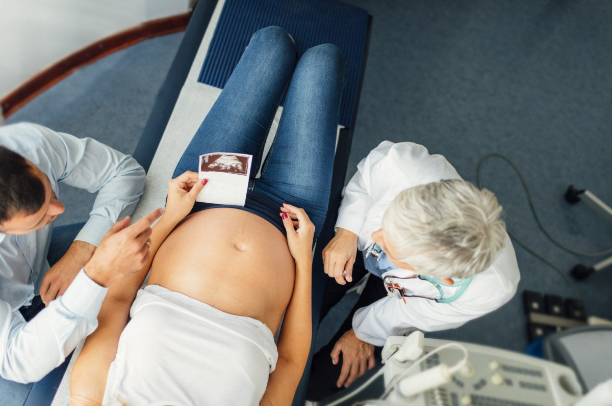 pregnant woman looking at her ultrasound scan picture in hospital along with doctor