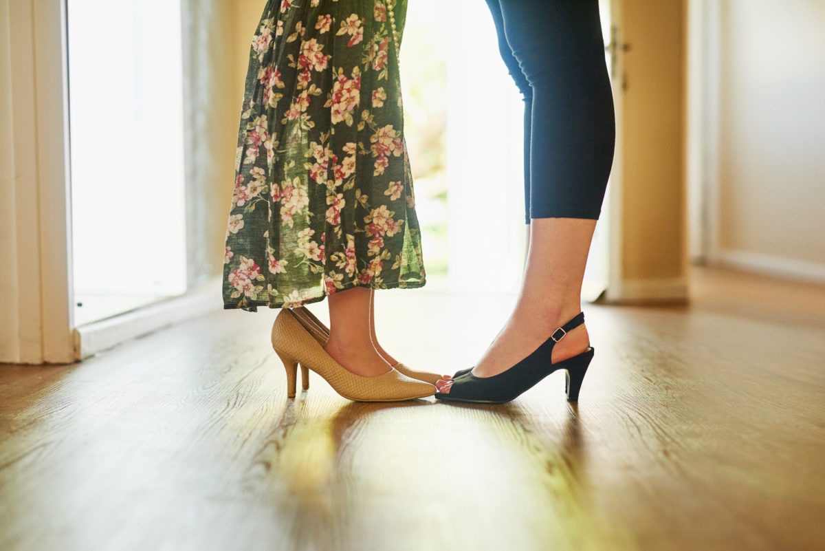 Little girl wearing heels with her mother in room