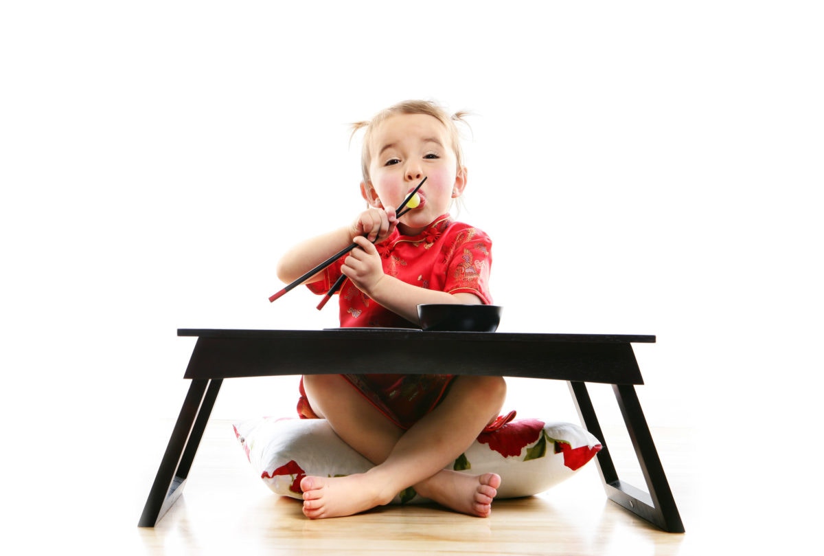 A child sitting on a pillow in front of a table