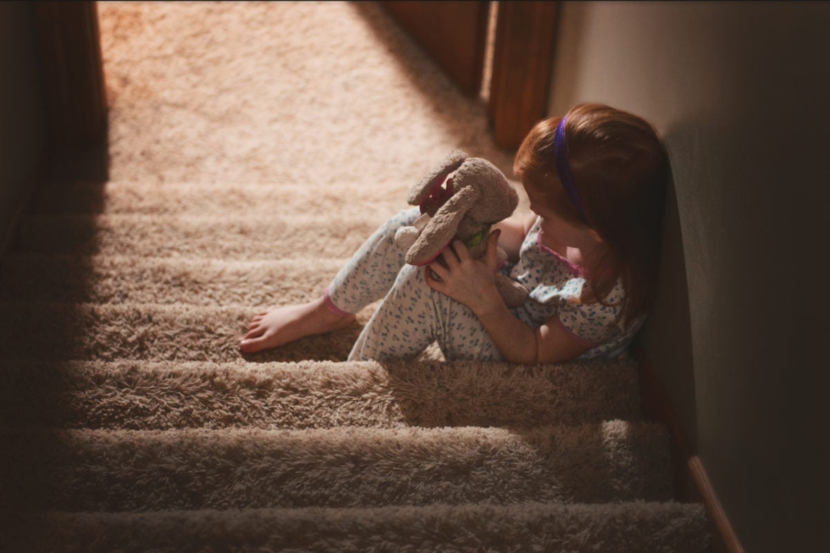 A child sitting on stairs holding teddy