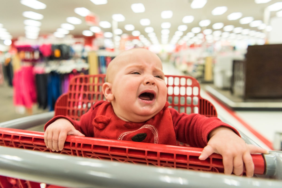 A child sitting on a shoping cart and crying