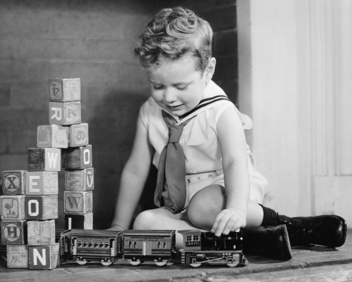 Black and white image of a child playing with toy train