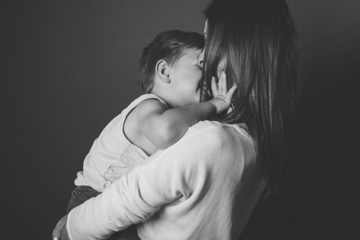 A child kissing his mother on her arms