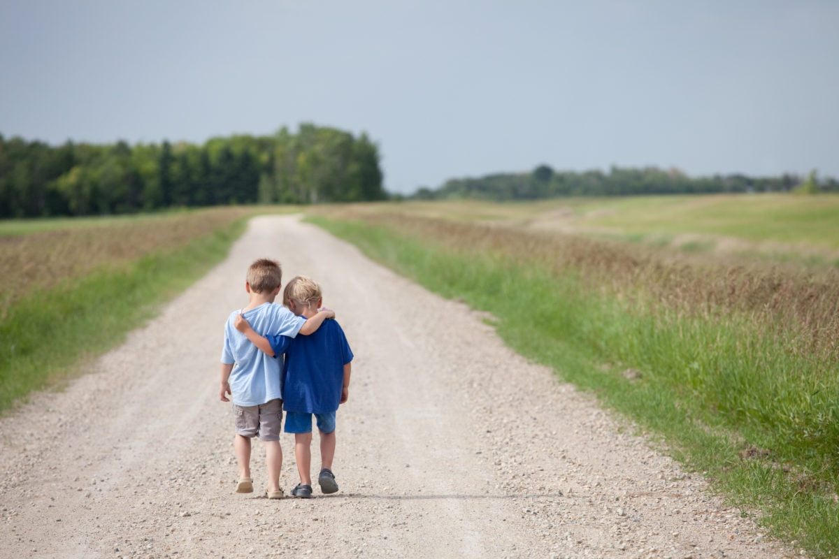 Two boys walking with arms around each other's shoulders