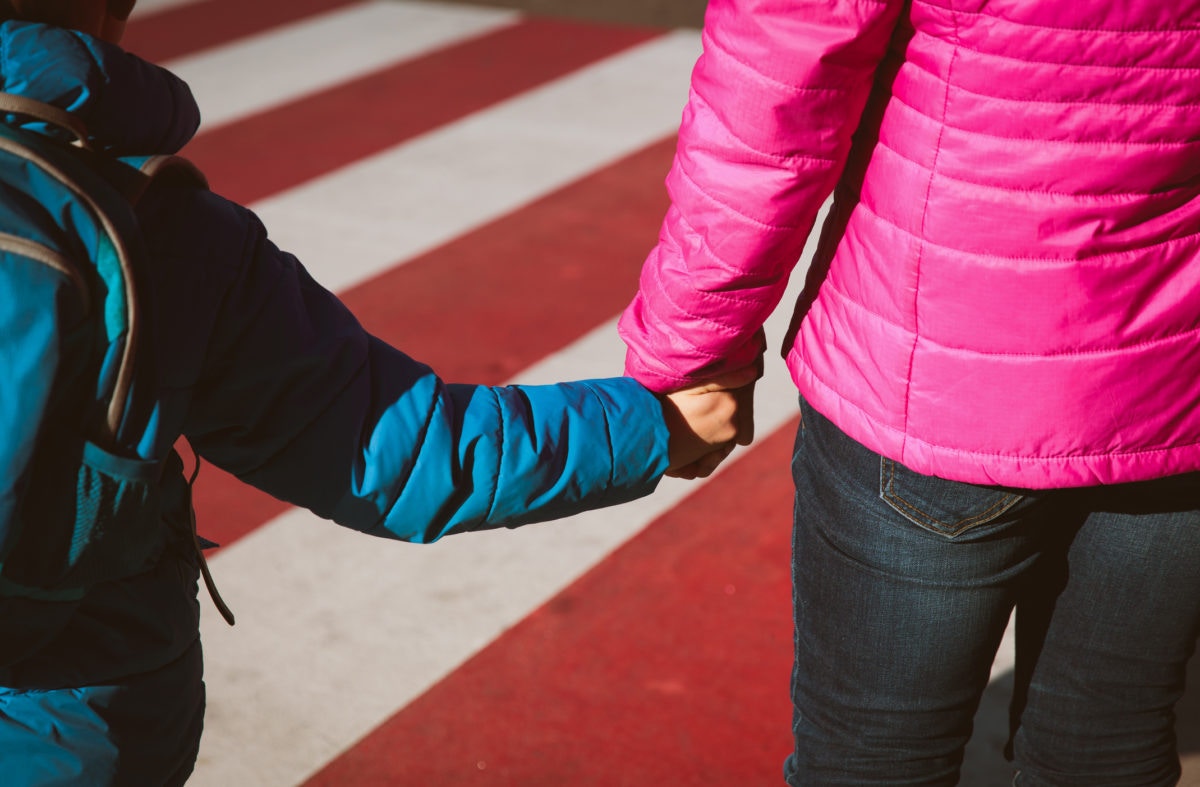 boy with backpack holding her mother hand