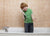 The boy standing in the bathtub  and talking on the phone