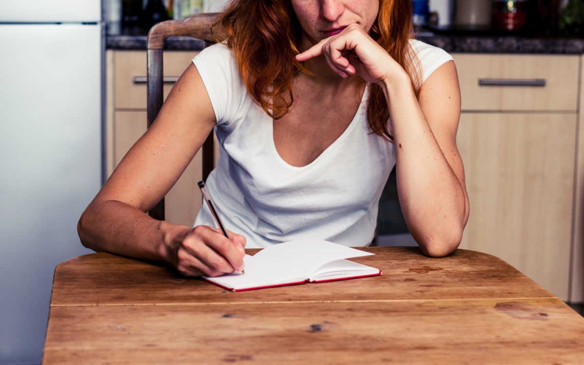 woman sitting at table writing in book