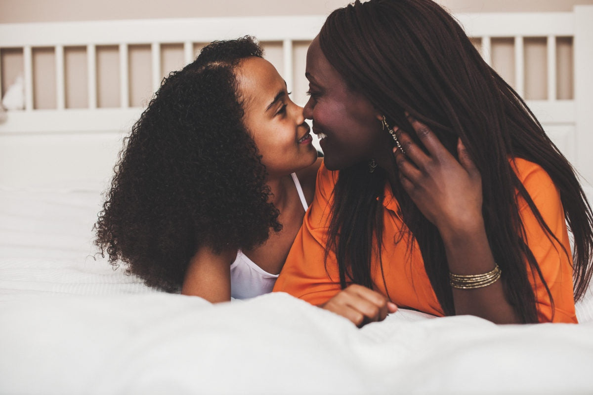 Close up of black mother and daughter kissing and smiling