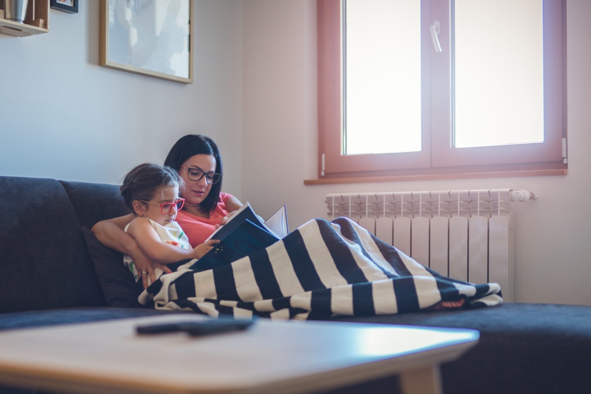 Mother reading book with her child on a blanket