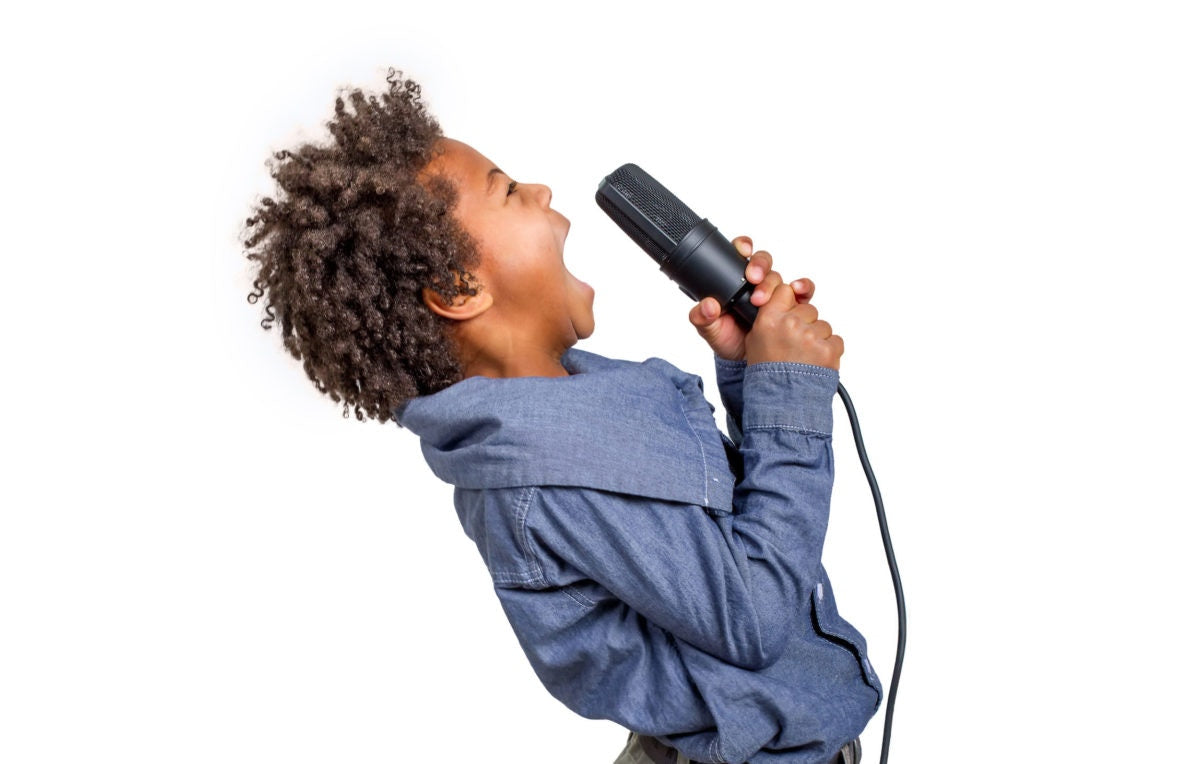 A kid singing a song holding  a microphone