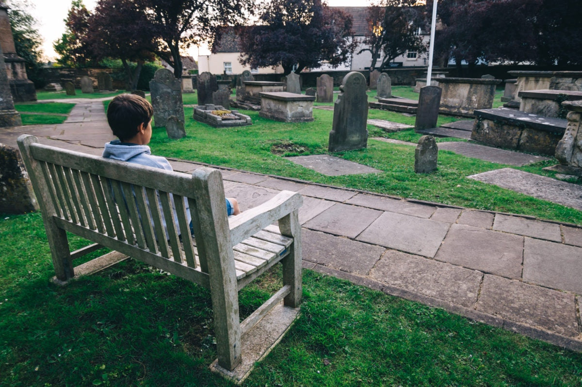 A boy is sitting in a burial ground