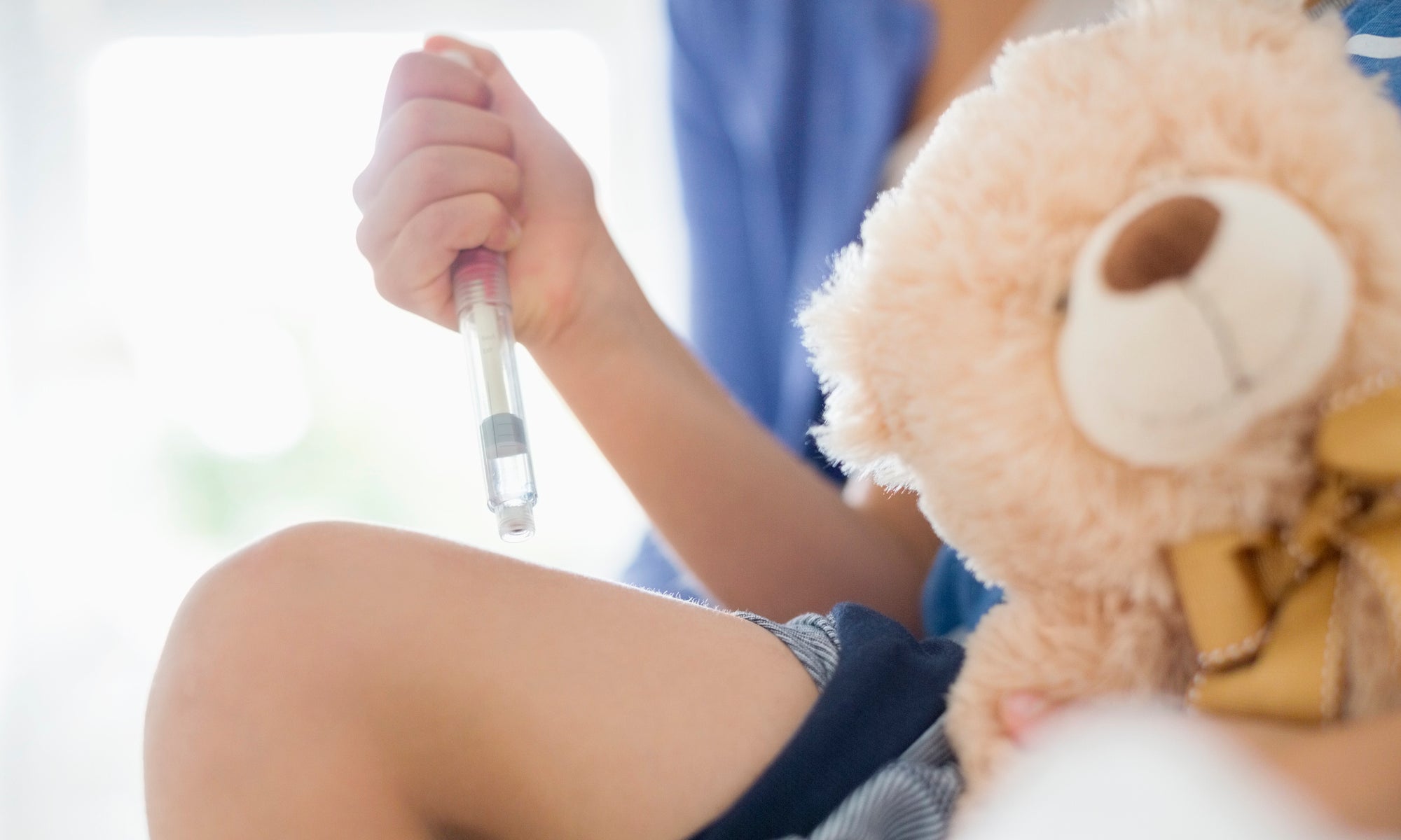 girl hand holding syringe and teddy bear