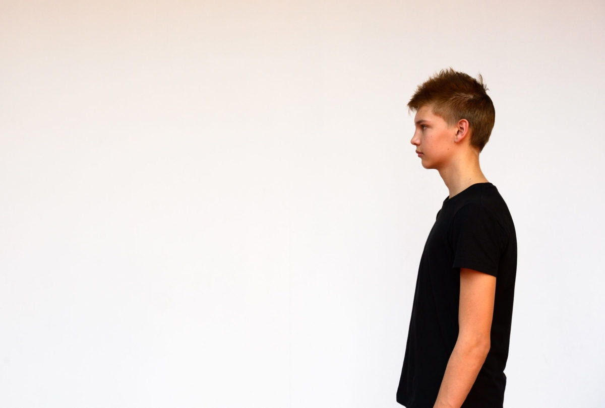 side view of a boy standing over  white background