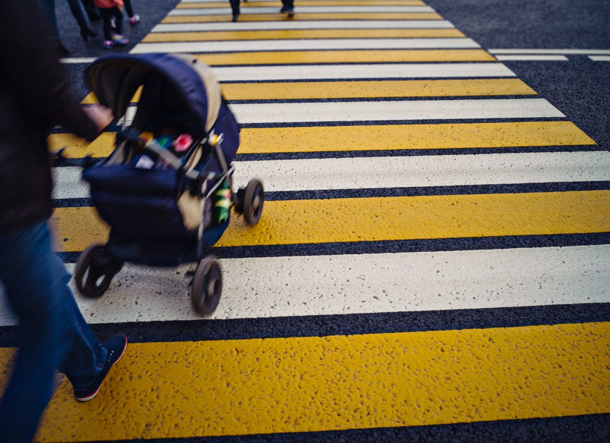 man crosses on zebra crossing with the stroller