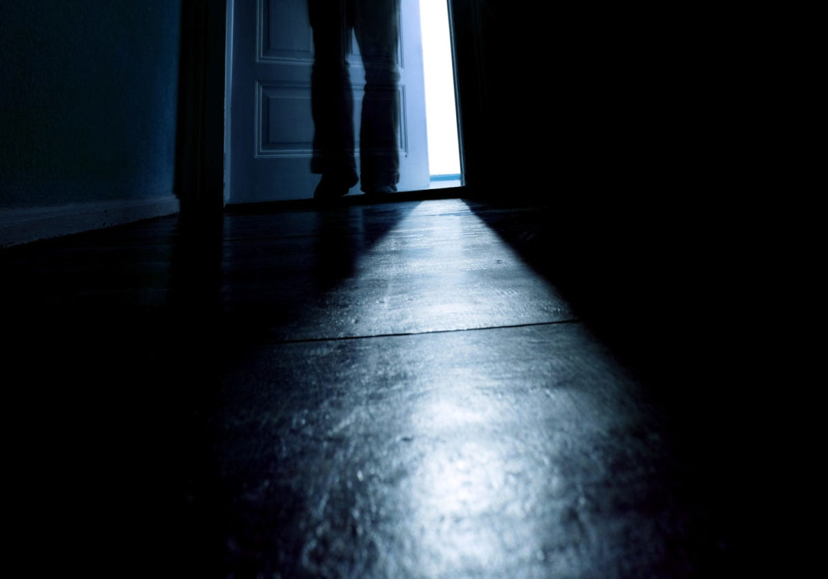 Person going out from a dark room, at the door