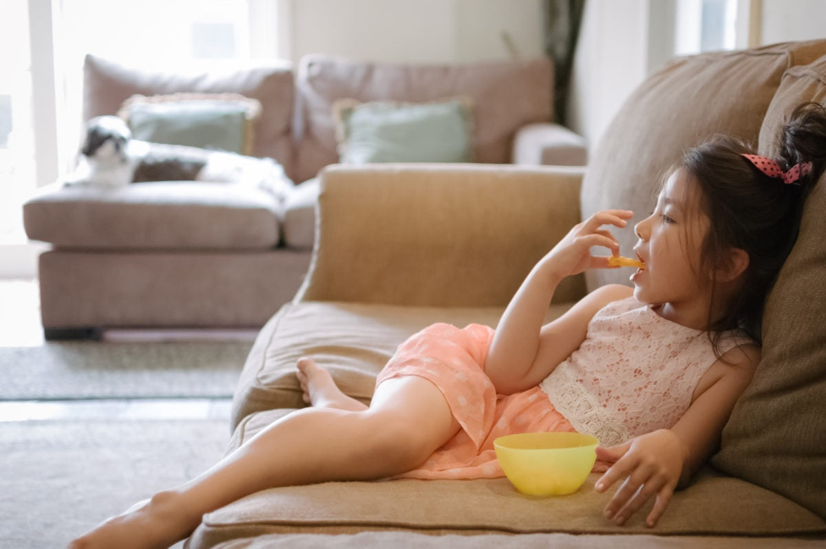 Girl sitting on sofa and eating chips