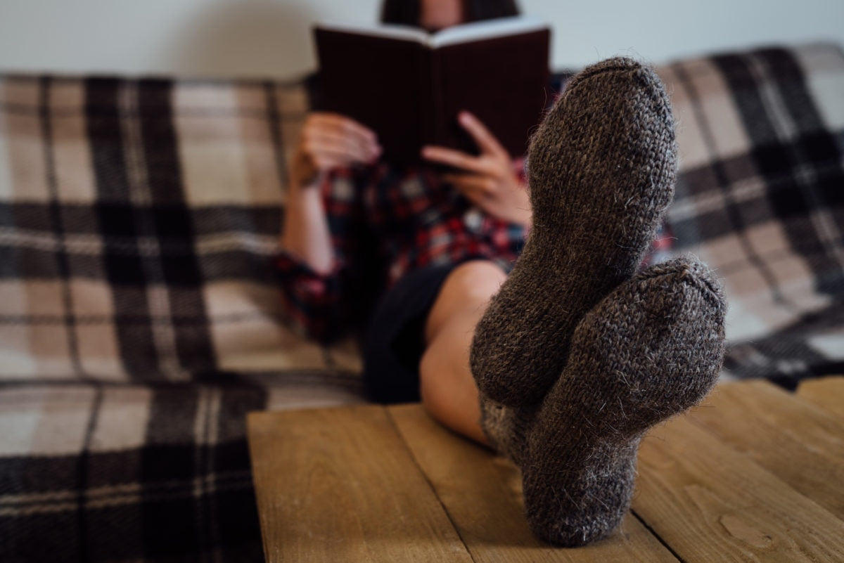 Young girl with grey socks lying on bed, reading book