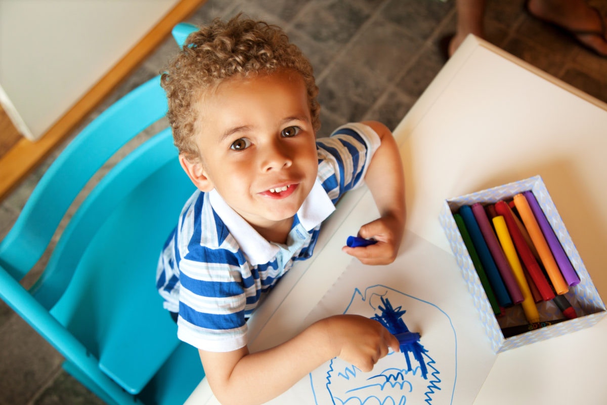 boy drawing with blue crayon color on the paper