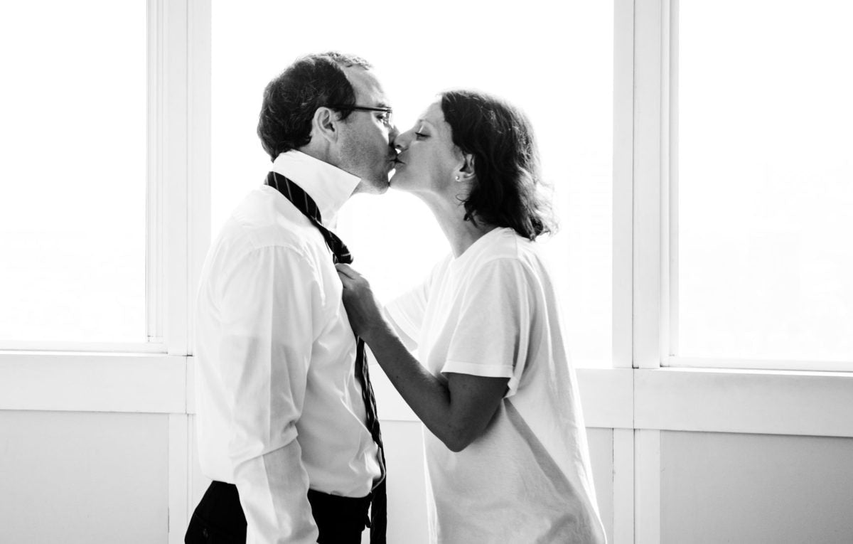 Wife tying tie for husband and kissing