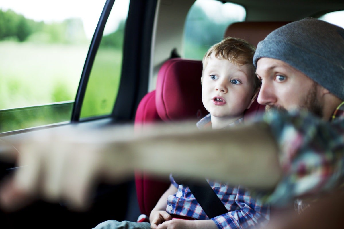 father shows his son something in the distance sitting in car