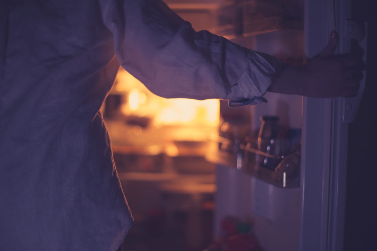 woman opening fridge at night