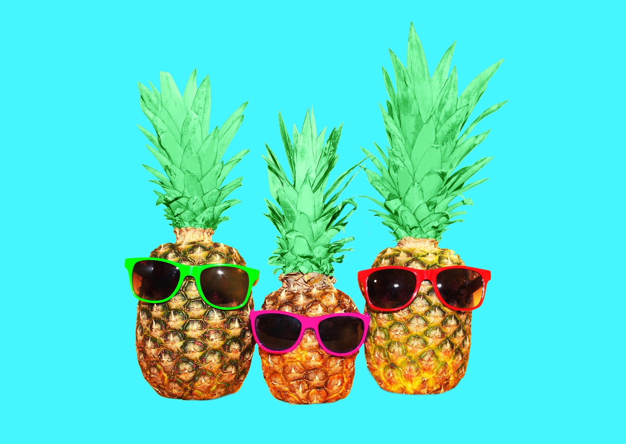 hree pineapple with sunglasses on mint background
