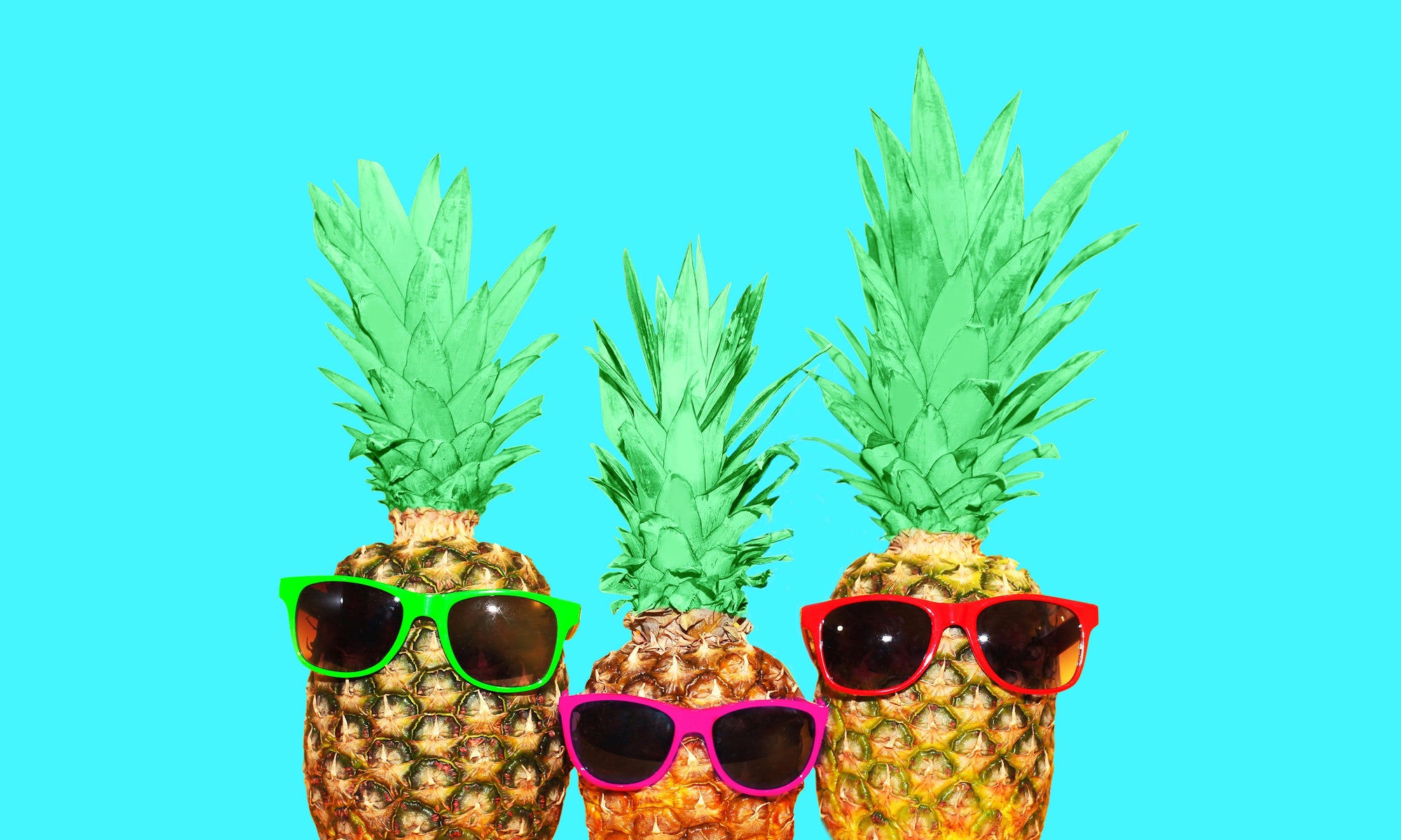 hree pineapple with sunglasses on mint background