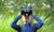 Boy in pith helmet looking up through big binoculars outdoors