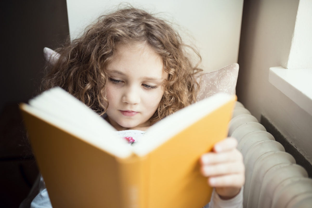 little girl with brown hair reading a book