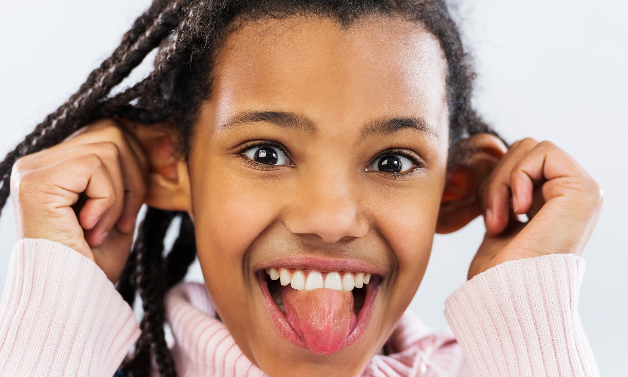 young girl sticking out her tongue and pulling her ears