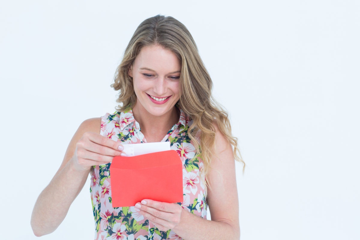 young woman looking at a card smiling