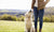 Girl is standing in a open field holding a dog