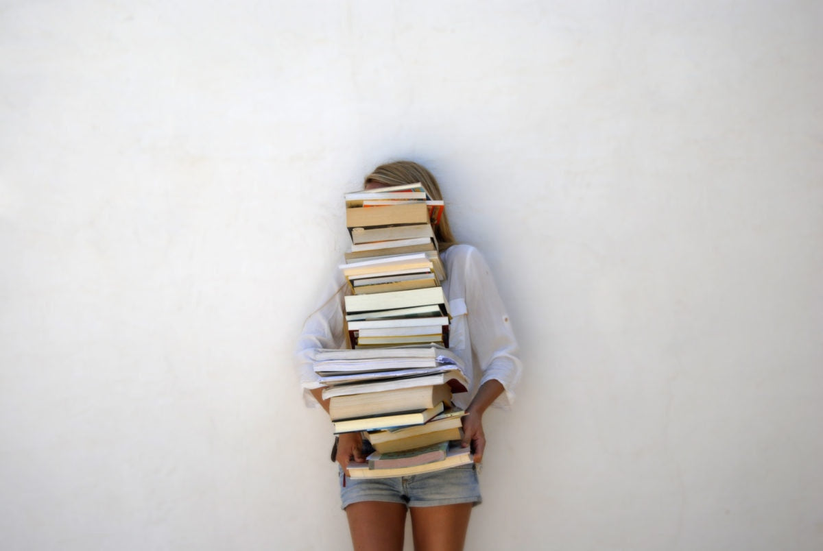 A girl is holding books by covering her face