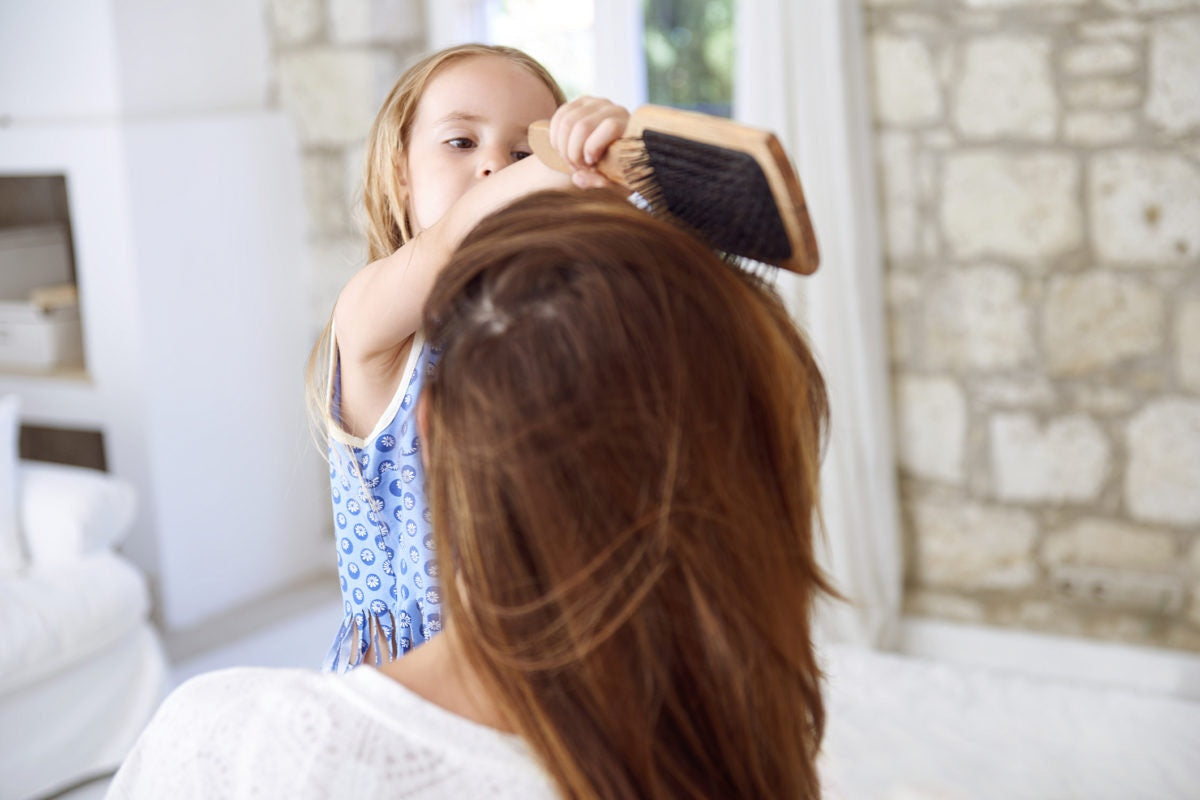young girl combing mom's hair